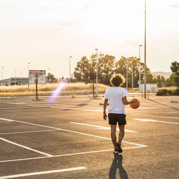 Rear view of a man playing basketball in court